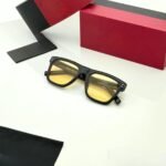 Black rectangular sunglasses with yellow tinted lenses and red temple accents