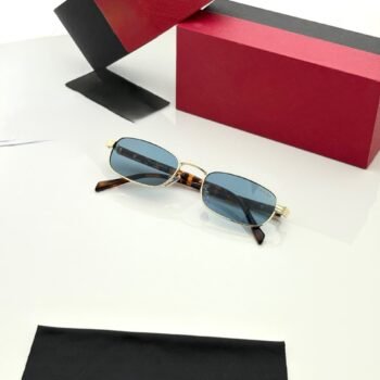Slim rectangular sunglasses with a gold-tone frame, blue lenses, and brown patterned temples