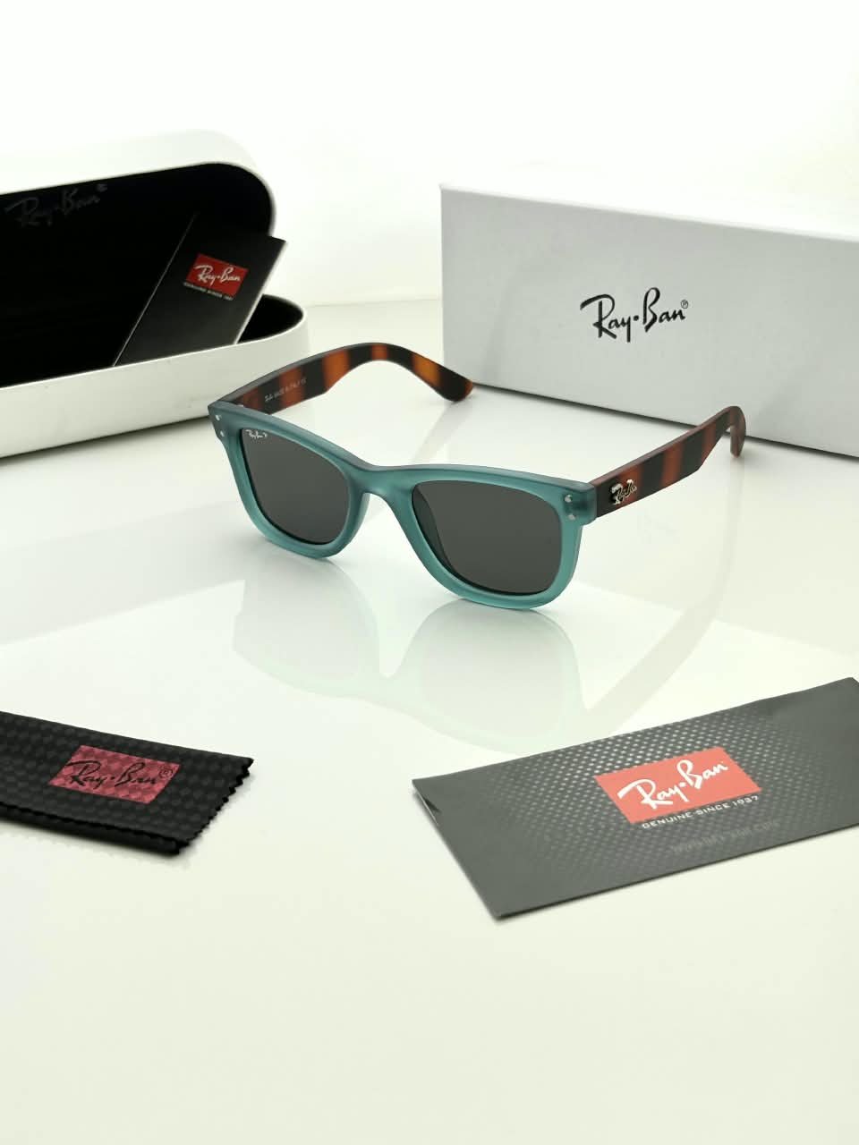 Teal Frame Sunglasses – Dark Grey Lenses (1) Teal rectangular sunglasses with dark grey lenses and brown patterned temples