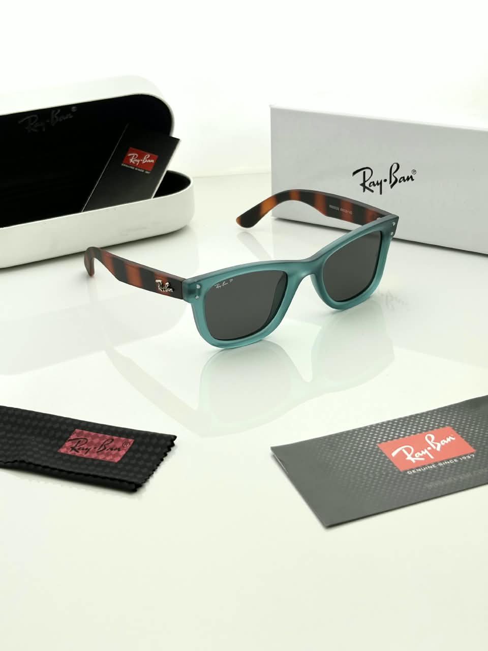 Teal Frame Sunglasses – Dark Grey Lenses (2) Teal rectangular sunglasses with dark grey lenses and brown patterned temples