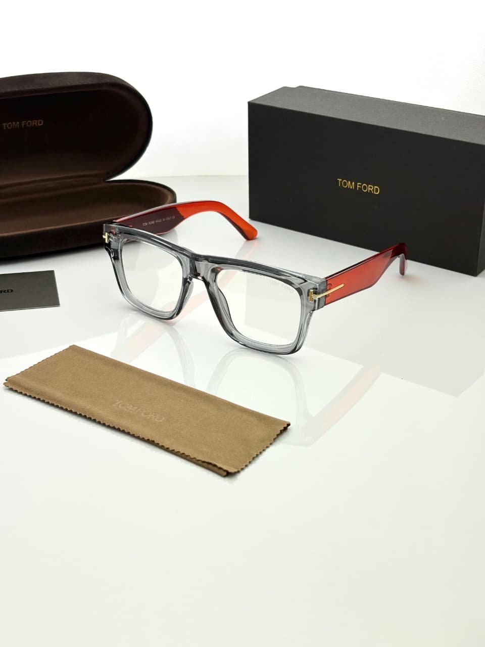 Transparent Grey Eyeglass Frames – Red Temple Design (1) Transparent smoky grey rectangular eyeglass frames with red temples and gold-tone hinge details