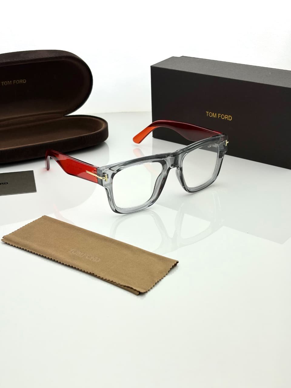 Transparent Grey Eyeglass Frames – Red Temple Design (2) Transparent smoky grey rectangular eyeglass frames with red temples and gold-tone hinge details